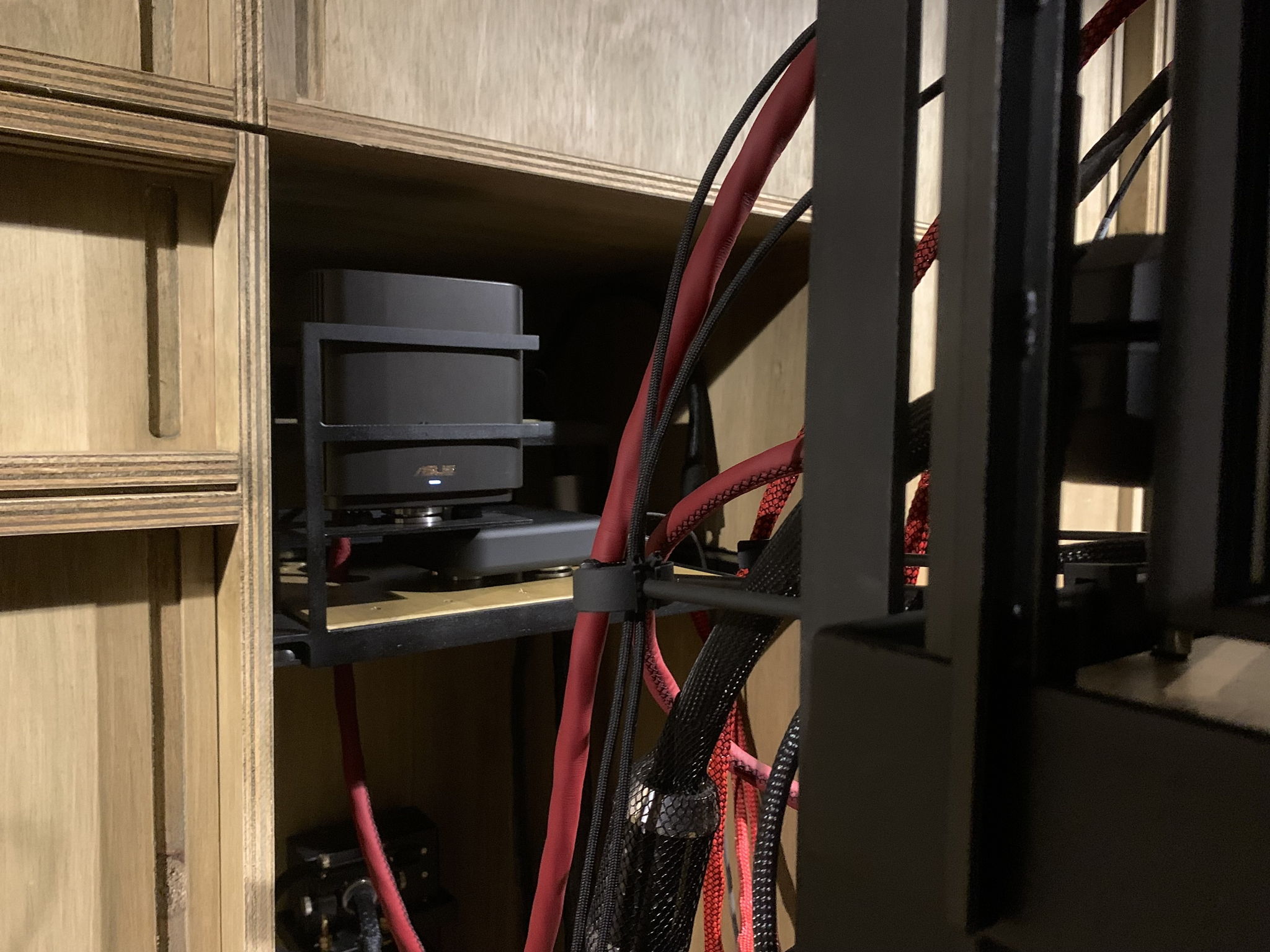ASus mesh Wi-Fi satellite router with Farad super3 linear power supply sitting on a separate custom isolation platform strung between plywood cabinet sides. Another farad super3 to the back of the shelf powers the taiko dc distributor.